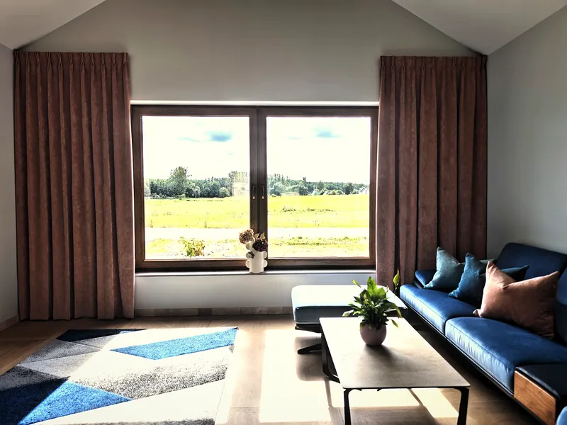 Zasłony w kolorze ciemnego bordo przy dużym oknie w salonie