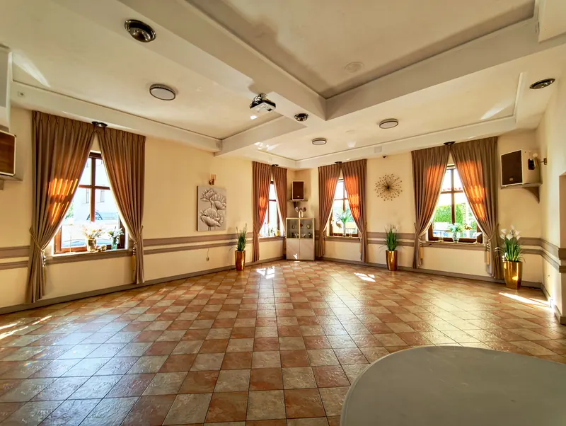 Sala weselna w Sulęcinie z beżowymi zasłonami podpiętymi złotymi chwostami na wszystkich oknach