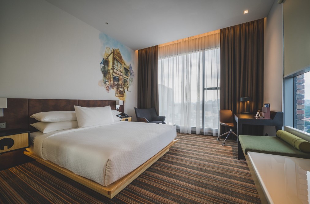 Nowoczesna sypialnia hotelowa z dużym oknem, zasłonami blackout i lekką firaną, zapewniającymi kontrolę światła i komfort wypoczynku