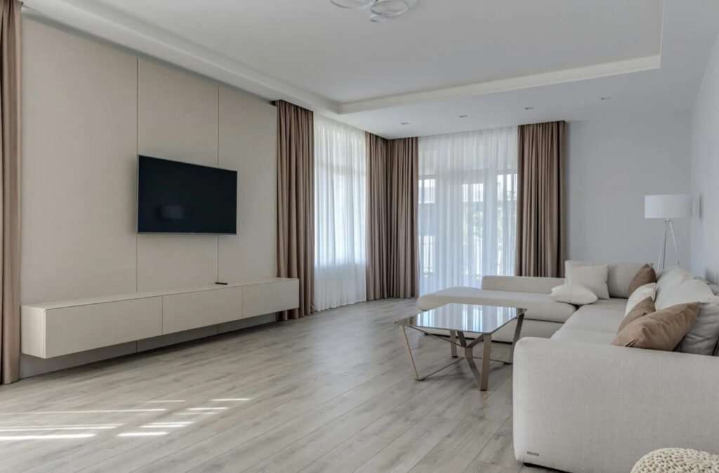 Salon z dużymi przeszkleniami i jasną aranżacją, wyposażony w długie zasłony i firany w systemie flex – eleganckie tkaniny okienne idealne do regulacji światła i prywatności we wnętrzu w Zielonej Górze